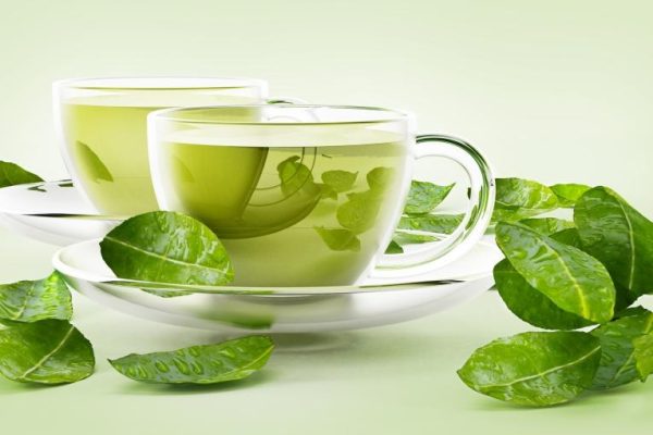Glass cups with green tea and tea leaves isolated on white